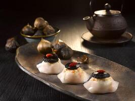 Steamed Dumpling with Minced Meat and Black Garlic served in dish isolated on table top view of food photo