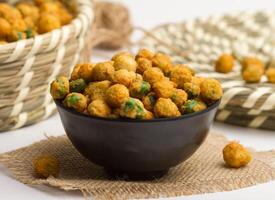 frito verde chícharos con chile servido en un cuenco aislado en servilleta lado ver de nueces en gris antecedentes foto