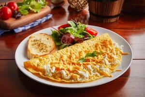 Triple Cheese omelette roll with salad served in a dish isolated on wooden background side view photo