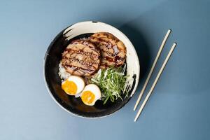 CHASU DON with egg, rice and chopsticks served in a plate isolated on background top view of japanese fast food photo