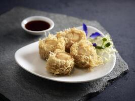 Crispy fried Yam Ring stuffed with Scallop served in a dish isolated on wooden board side view dark background photo