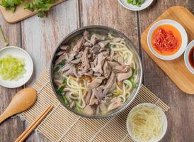 Pork meat Noodle soup with chilli sauce, noodles, spoon and chopsticks served in dish isolated on napkin top view of hong kong food photo