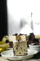 Oreo Cheesecake slice include chocolate, cream, sugar with fork and flowers served in plate isolated on napkin side view of cafe food photo