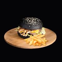 Black Ashes Cheese Burger with french fries served on wooden board side view on black background fast food photo