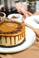 Salted Caramel Blondie cake include chocolate cream, sugar with fork, cup of coffee and pot served on board isolated on napkin side view of cafe food photo