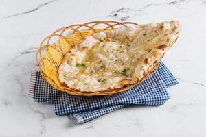 crujiente ajo naan en un cesta aislado en servilleta lado ver en gris antecedentes famoso indio y pakistaní comida foto