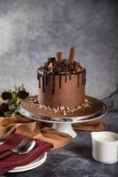 Chocolate Overloaded Cake with rose flowers, knife and fork served on board isolated on napkin side view of cafe baked food photo