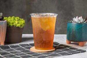 Meng Po tea served in disposable glass isolated on wooden board side view of taiwanese ice drink photo