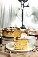 Salted Caramel Blondie cake slice include chocolate cream, sugar with fork, cup of coffee and pot served plate isolated on napkin side view of cafe food photo