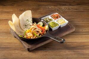 Mexican chicken fajita with bell peppers, grilled vegetables and onions top view on dark wooden background photo