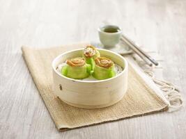 Steamed Prawn Dumpling with Abalone served in a wooden bowl with chopsticks isolated on mat side view on grey marble background photo