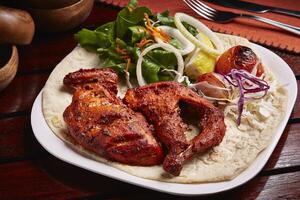 Grilled Tandoori Chicken with bread, salad and lemon served in dish isolated on table side view of middle east food photo