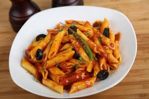 Penne Arrabiata pasta with olive and sauce served in a dish isolated on table side view of middle east food photo