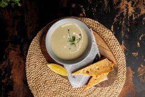 Cream Chicken soup with bread and lime served in dish isolated on table top view of arabic breakfast photo