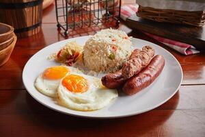 Brunch breakfast with sausages, fried rice and eggs served in a dish isolated on wooden background side view photo