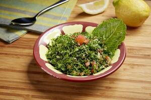 Fresh green Taboule or tabbouleh with tomato, green leaf and lime slice served in dish isolated on table side view of middle east food photo