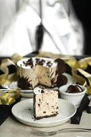 Oreo Cheesecake slice include chocolate, cream, sugar with fork and flowers served in plate isolated on napkin side view of cafe food photo