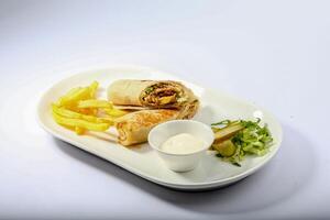 Chicken Wrap shawarma with fries, salad and dip served in a dish isolated on grey background side view of arabian fastfood photo