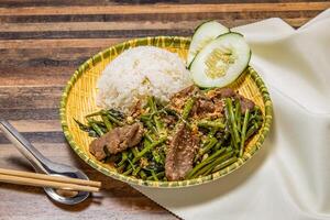 Belacan Water Spinach and beef with Rice with cucumber and chopsticks served in dish isolated on wooden table top view of hong kong fast food photo