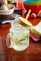 A jar of healthy fresh LIME AND MINT drink with straw isolated on wooden background side view photo