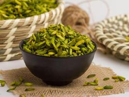 Green pistachio sticks served in a bowl isolated on napkin side view of nuts on grey background photo