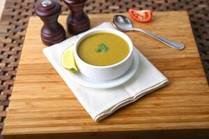 lentil Soup with spoon, lime slice and tomato served in bowl isolated on table side view of middle east food photo