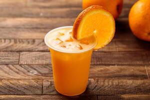 frehs naranja jugo con crudo naranja rebanada servido en vaso lado ver en de madera mesa Mañana comida foto