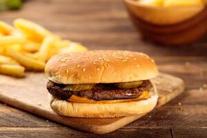 Beef Burger with fries served in a cutting board isolated on wooden table background side view of fastfood photo