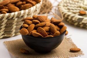 Almonds served in a bowl isolated on napkin side view of nuts on grey background photo