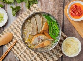 Duck meat rice noodles with chilli sauce, noodles, spoon and chopsticks served in dish isolated on napkin top view of hong kong food photo