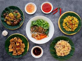 viet mar tofu con La hierba de limón, mezclado pegajoso arroz fideos, pollo corazón y pulmones, frito maíz, profundo frito cerdo intestino ensalada servido en cuenco aislado en oscuro gris antecedentes parte superior ver de japonés comida foto