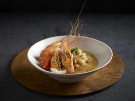 Braised Hor Fun with Prawn in Lobster Broth served in a dish isolated on cutting board side view on dark background photo