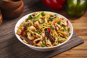 Mixed Noodles with vegetable, meat and chicken served in dish isolated on table side view of middle east food photo