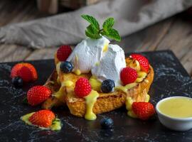 french toast with strawberry, blackberry, cream and basil served in a dish isolated on cutting board side view of breakfast on wooden background photo