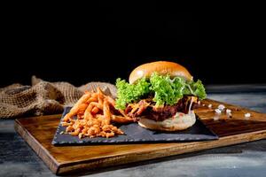 beef burgers with tomato, cheese, ketchup and french fries in a black dish top view on dark background photo