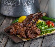 lamb chops served in dish side view on wooden table background photo