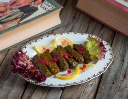 Vine leaves or wine leaves served in a dish isolated on wooden background side view of appetizer photo