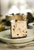 Oreo Cheesecake slice include chocolate, cream, sugar with fork and flowers served in plate isolated on napkin side view of cafe food photo