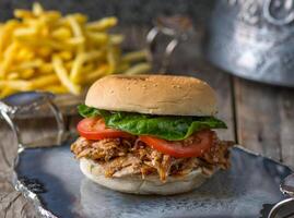 crispy chicken burger with fries served in wooden board side view on wooden table background served in dish side view on wooden table background photo