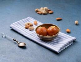 Gulab jamun with nuts served in a dish isolated on napkin side view on dark background indian sweet photo