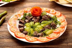 Grilled liver with salad served in a dish isolated on wooden table background side view of fastfood photo