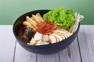 Korean Ramen Spicy Miso with pork, egg and mushroom, vegetables in a blue bowl on wooden table photo