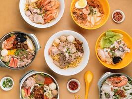 chinese seafood table with Tom Yum, Xiao Wan, Sliced Fish, Porridge, Bee Hoon, Black Soya Sauce, in a bowl with soup, chili sauce, spring onion top view on wooden table chinese seafood noodle table photo