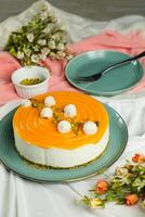 Mango Yogurt Cake topping with pistachio fork and flowers served in plate isolated on napkin side view cafe bake food photo
