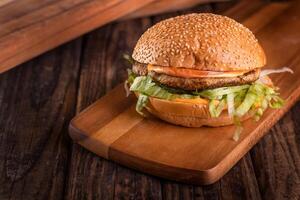 Grilled Chicken burger isolated on cutting board top view on dark background american fast food photo