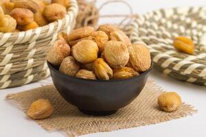 Dry apricot served in bowl isolated on napkin side view of dry fruits on grey background photo