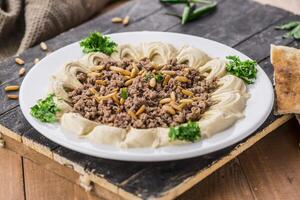 Hummus with meat and pine nuts served in dish isolated on table side view of arabic food photo