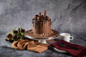 Chocolate Overloaded Cake with rose flowers, knife and fork served on board isolated on napkin side view of cafe baked food photo