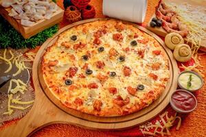 Seafood pizza with tomato sauce and mayo isolated on wooden board top view of italian food on wooden background photo