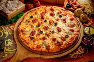 Seafood pizza with tomato sauce and mayo isolated on wooden board top view of italian food on wooden background photo